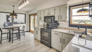 Una cocina moderna con suelo de madera clara, una isla central y un comedor con mesa y sillas redondas.