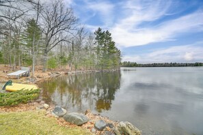 A calm lake with a dock and a yellow kayak, surrounded by trees and a clear sky. - Waterfront Cabin w/ Deck: Serene Eddington Escape (Eddington)