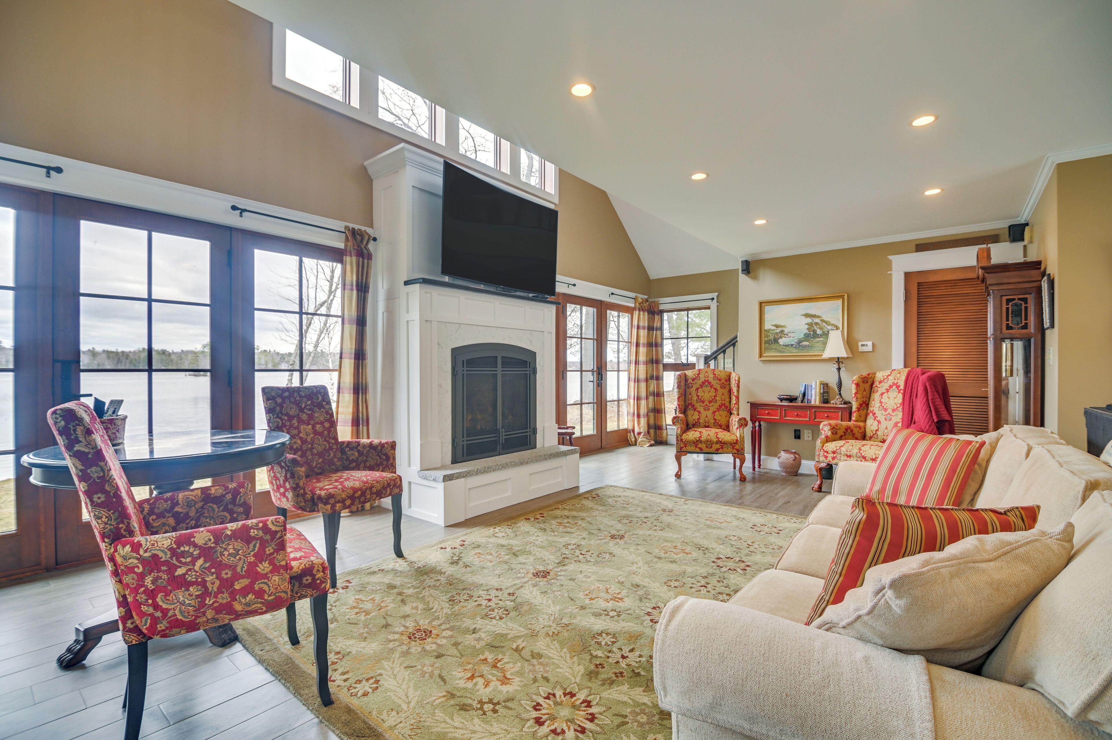 A spacious living room with a fireplace, large windows, and a cozy seating area.