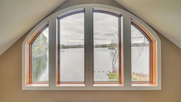 Ein Zimmer mit einem großen Bogenfenster mit Blick auf einen See.