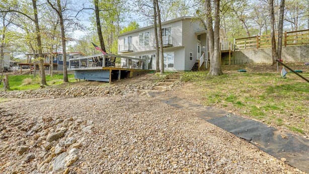 A two-story house with a balcony, a deck, and a stone pathway leading to the entrance. - Balcony & Fire Pit: Home on Lake of Ozarks! (Roach)
