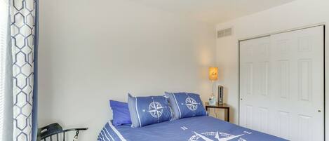A bedroom with a bed, a chair, a nightstand, and a door.