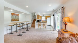 A spacious kitchen with a central island, a dining area with bar stools, and a cozy seating area with a lamp. - Balcony & Fire Pit: Home on Lake of Ozarks! (Roach)