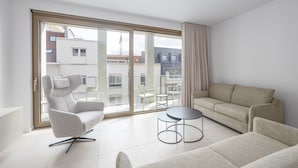 Un salon moderne avec un canapé, un fauteuil et une petite table ronde.