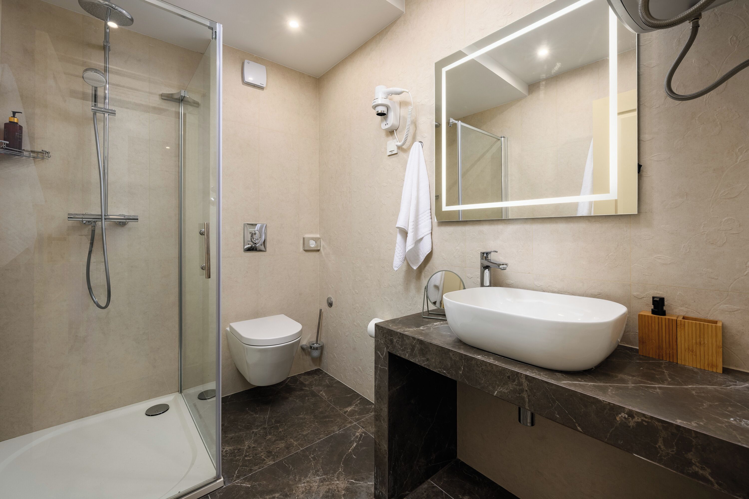 Une salle de bain moderne avec une douche à parois de verre, un lavabo blanc et un grand miroir.