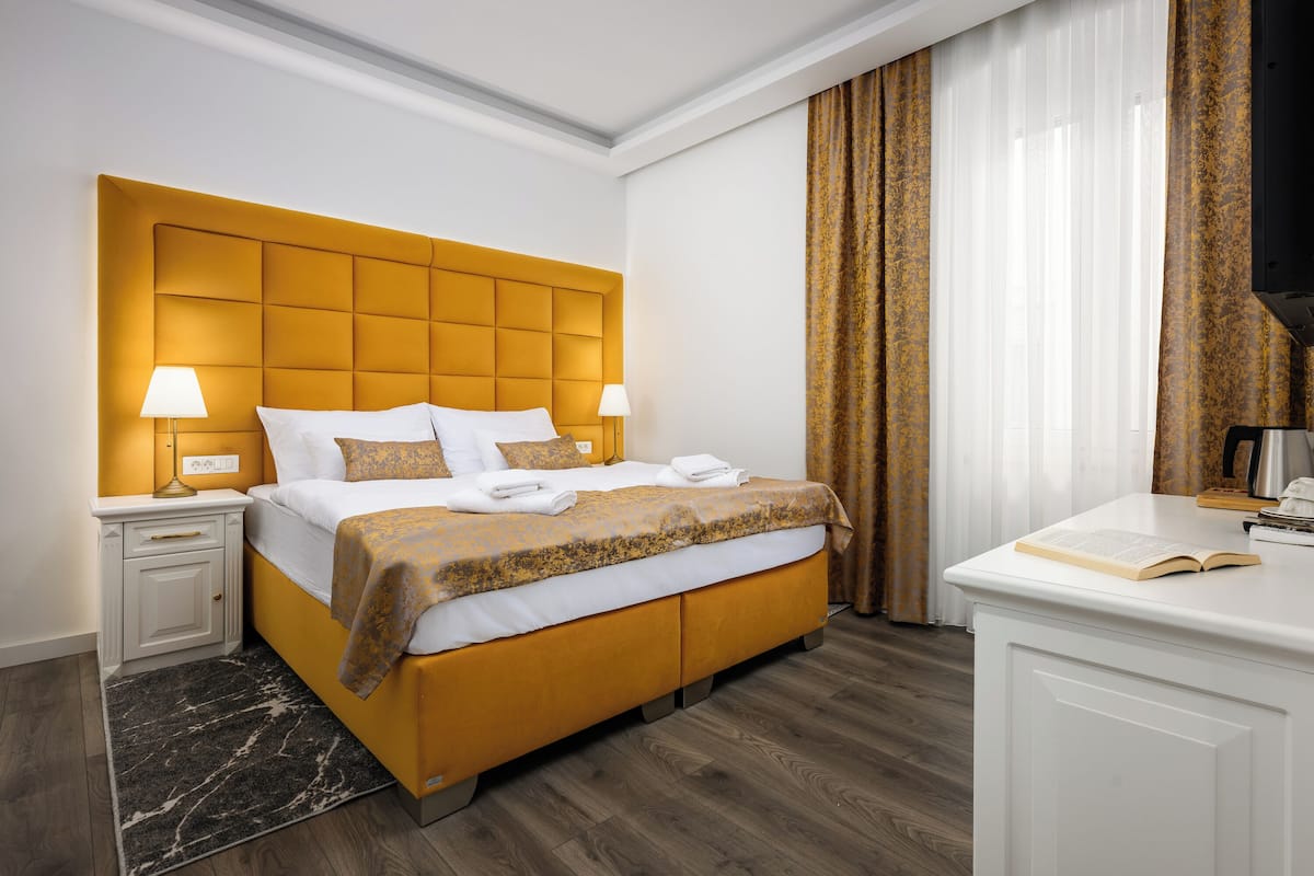 A hotel room with a large bed, two bedside tables, a desk, and a television.