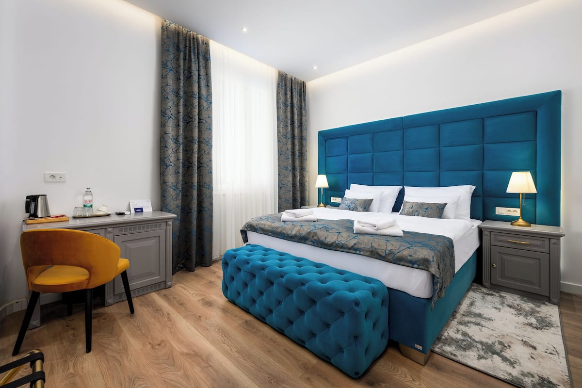 A modern hotel room with a large bed, a desk, and a chair.