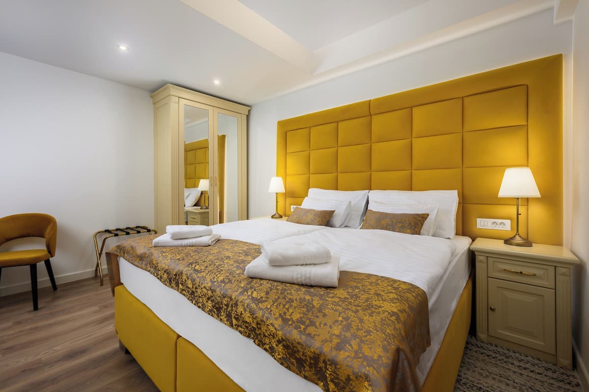 A hotel room with a large bed, two bedside lamps, a wardrobe, and a chair.