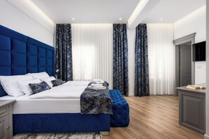 Un dormitorio moderno con una cama grande, cabecera azul y suelo de madera.