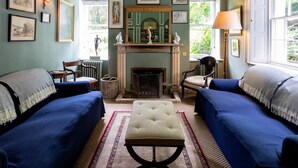 A traditional room with two blue sofas, a fireplace, and a large window.
