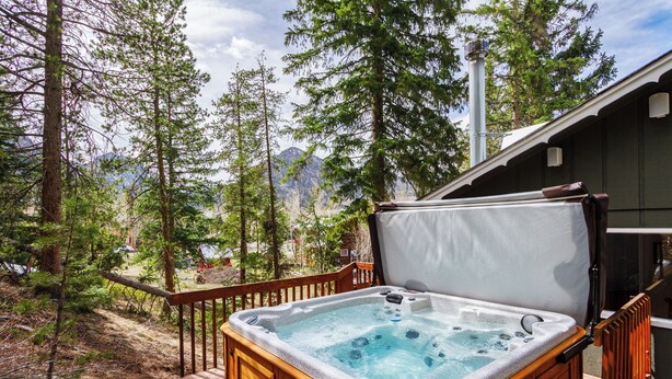 A hot tub in a forested area with a wooden deck and a view of mountains. - Frisco Mountain Retreat- Private Hot Tub (Frisco)
