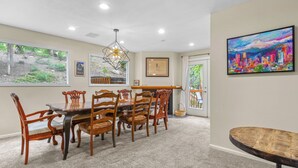 A dining area with a large table and chairs, a chandelier, and a cityscape painting on the wall. - Frisco Mountain Retreat- Private Hot Tub (Frisco)