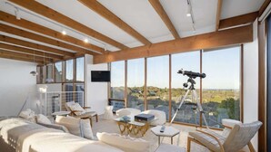 Une chambre moderne dotée d’une grande fenêtre, d’un télescope et d’un coin salon confortable.