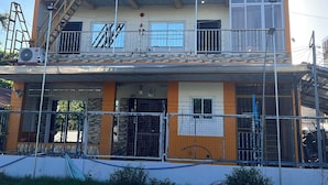 A multi-story building with balconies, a fire escape, and a gated entrance.