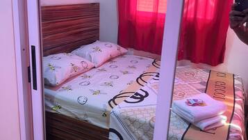 A bedroom with a wooden bed, a mirror, and a red curtain.