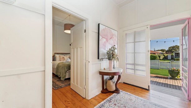 Um quarto com cama, porta que dá para uma varanda e uma obra de arte emoldurada na parede.