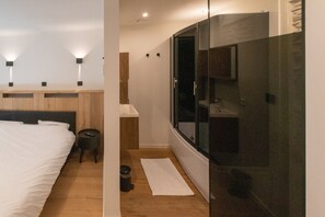 A modern hotel room with a large bed, a small stool, a trash bin, a window, and a wardrobe. - Holiday Home in La Roche With Castle Views (La Roche-en-Ardenne)