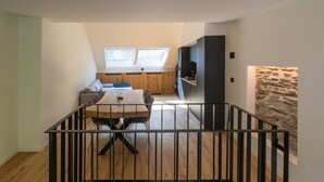 A modern interior with a dining area, kitchen, and a stone accent wall. - Holiday Home in La Roche With Castle Views (La Roche-en-Ardenne)