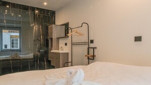 A hotel room with a large bed, a bathroom with a mirror, and a view of a building outside. - Holiday Home in La Roche With Castle Views (La Roche-en-Ardenne)