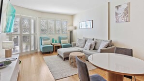 A modern living room with a sofa, ottoman, and round table.