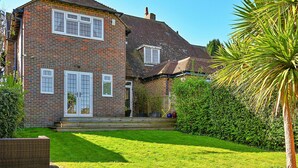 A two-story brick house with a well-maintained lawn and a palm tree.
