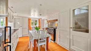 A modern kitchen with white cabinetry, a dining table with chairs, and a built-in oven. - The Nook (Goulceby)