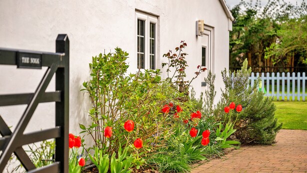 A white building with a black gate labeled "THE NORK" and a brick pathway leading to it. - The Nook (Goulceby)