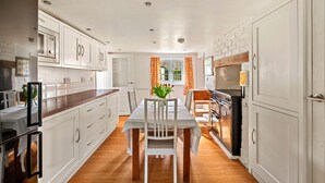 A modern kitchen with white cabinets, a wooden countertop, and a dining table with chairs. - The Nook (Goulceby)