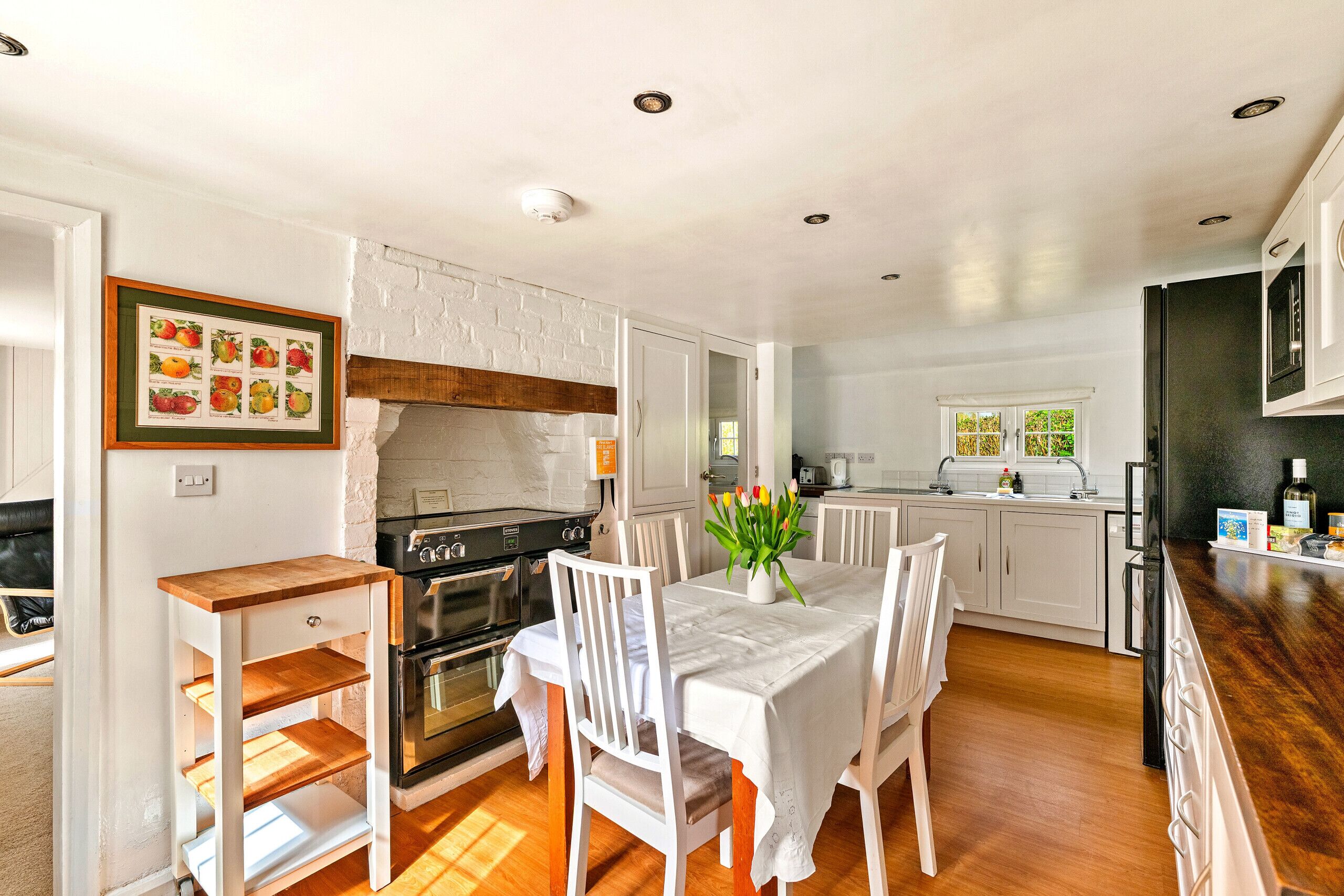 Une cuisine moderne avec des meubles blancs, une table en bois et une chaise blanche.