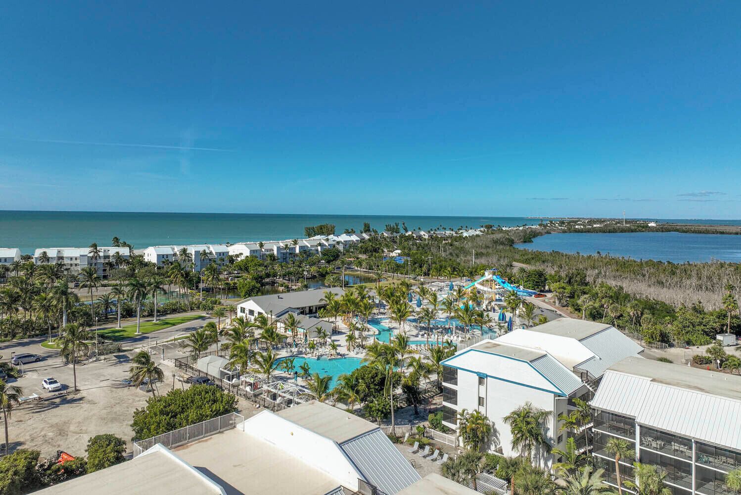 Un resort con varias edificaciones, un área de piscina central y vista al océano.
