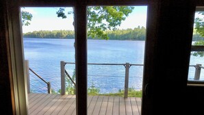 A wooden deck with a metal railing overlooking a lake.