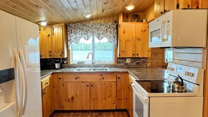 A kitchen with wooden cabinets, a refrigerator, a stove, and a microwave.