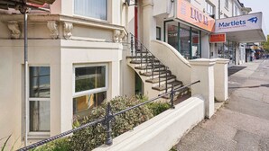 A building with a staircase leading to a door, a sign for Martlets, and a sign for LUO LI.