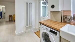 A modern kitchen with a built-in washing machine, a radiator, and a window with a view.