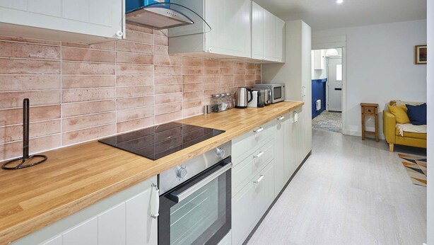 A modern kitchen with a wooden countertop, stainless steel appliances, and a tiled backsplash.