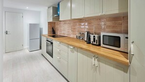 A kitchen with light-colored cabinets, a wooden countertop, a microwave, a toaster, and a kettle.