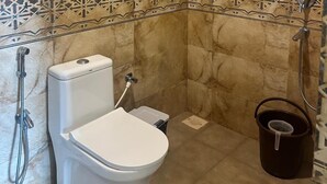 Ein Badezimmer mit Toilette, Dusche und dekorativ gefliesten Wänden.