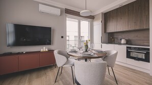 A modern kitchen with a dining area, a flat-screen TV, and a built-in oven. - Industria Apartment Zawisza Parking Balkon (Bydgoszcz)