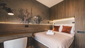A modern bedroom with a wooden headboard, a bed with white and orange pillows, a nightstand, and a desk with a chair. - Industria Apartment Zawisza Parking Balkon (Bydgoszcz)