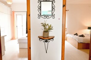 A bedroom with a bed, a bedside table with a plant, a mirror, and a door leading to another room. - Seaview Apart 5mn From Sea Xemxija (St. Paul's Bay)