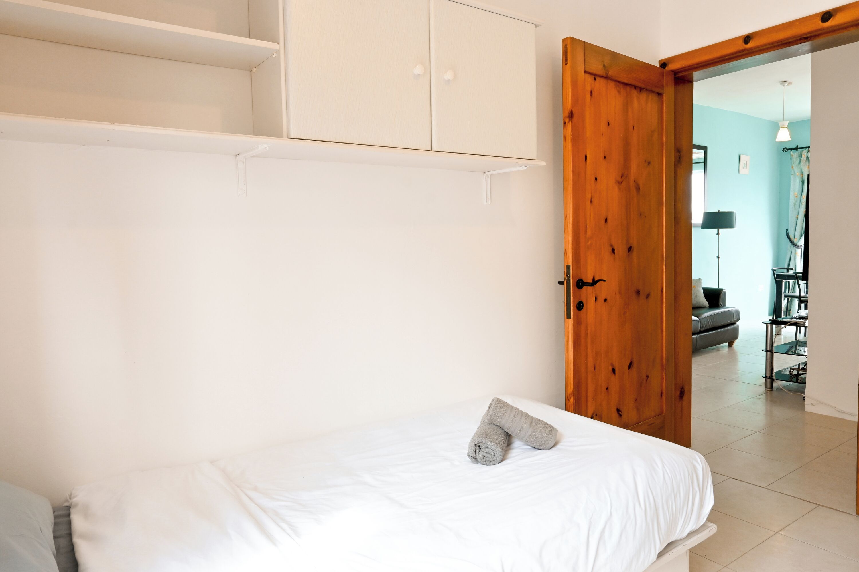 A room with a bed, a wardrobe, and a wooden door leading to another room.