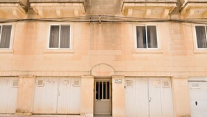 A building with a symmetrical facade, featuring a central entrance with a door and windows on either side. - Sea & Valley Views Żebbuġ Gozo (Zebbug)