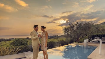 Ein Paar steht am Pool mit Blick auf den Sonnenuntergang.