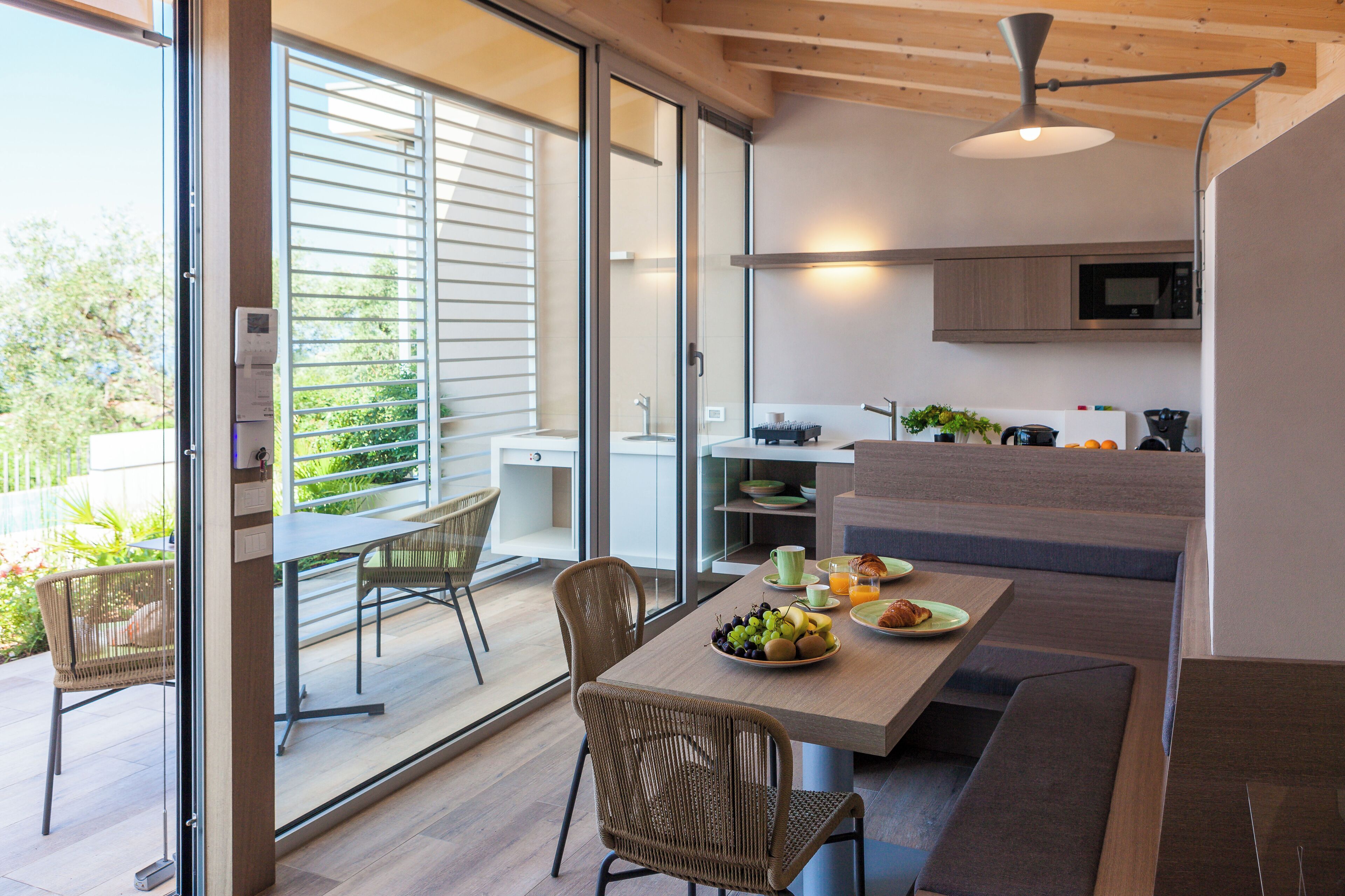 Une cuisine moderne avec un coin repas, de grandes fenêtres et une vue sur l’extérieur.