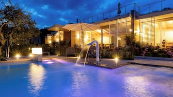 Una piscina al aire libre, sombrillas, sillones reclinables de piscina