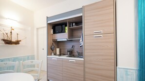 A compact kitchen with a microwave, sink, and storage cabinets.