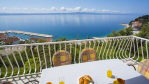 A balcony with a table set for breakfast, overlooking a marina and a calm sea. - Sea View Apartments Lendic Podgora (Podgora)