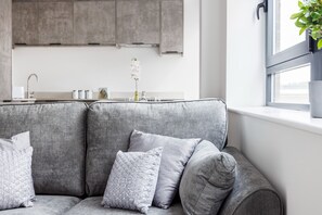 A grey sofa with multiple cushions in a modern kitchen setting. - Modern 1 Bed Flat in Town Centre - Free Wifi (Luton)