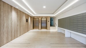 A modern hallway with wooden paneling, a row of mailboxes, and two elevators. - Modern 2 bed Flat in Town Centre - Free Wifi (Luton)