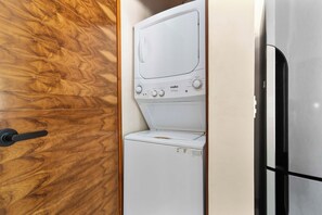 Een compacte wasmachine en droger combinatie met een houten deur en een zwarte hendel.